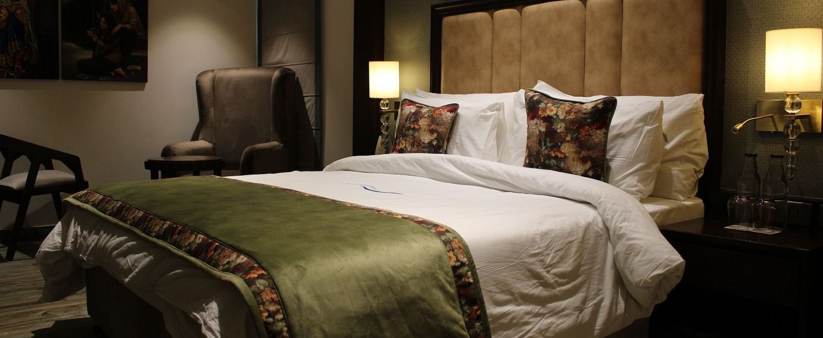 Side view of the bedroom with multiple pillows arranged on the bed and a huge chair next to it at BluSalzz Residence, Amritsar